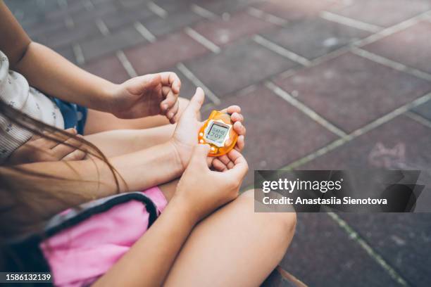 hands of children playing with electronic toy - tamagotchi stockfoto's en -beelden