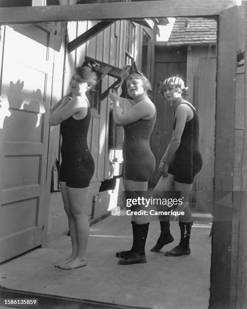 Three of Mack Sennett's 'Bathing Beauties' in one piece costumes reflected in a mirror as tehy prepare.