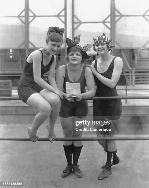 Three Mack Sennett's 'Bathing Beauties' in one piece bathing suits and swimming caps pose for a picture.
