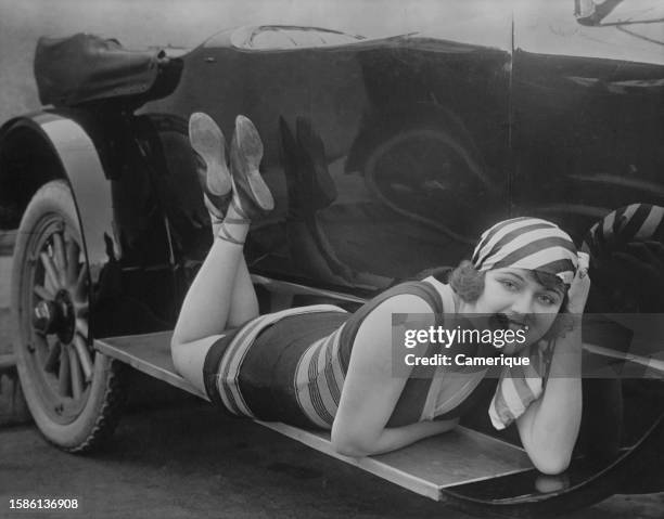 One of Mack Sennett's bathing beauties lying on the running board of a car.