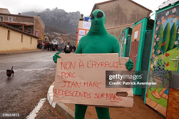 Man dressed as an alien holds up a sign after the time passed 11.11 am, the time the Mayan Apocalypse was supposed to occur in Bugarach village on...