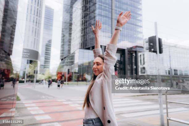 young woman with raised hands at the crossing in the city center - daily life in warsaw foto e immagini stock