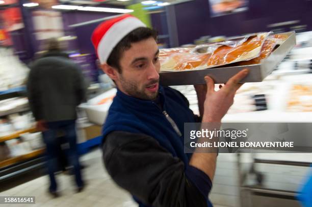 An employee carries products at the fish department of a supermarket on December 21, 2012 in Montesson, near Paris, a few days ahead of Christmas....