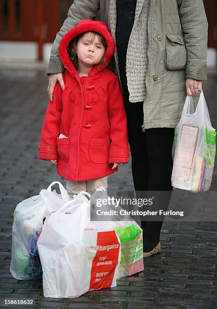 Three-year-old Lexie Hay poses beside her mum outside Liverpool Foodbank after collecting essential provisions for Christmas on December 21, 2012 in...