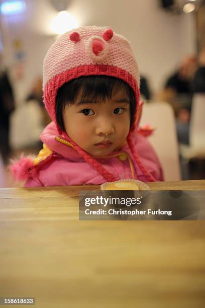 Ziyi Fang, aged 2, is given a cupcake as she waits with her mother to collect essential Christmas food at Liverpool Central Foodbank on December 21,...