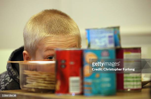 Eight-year-old Ryan Morris hides behind donated food for Christmas as his family collect essential provisions at Liverpool Foodbank on December 21,...