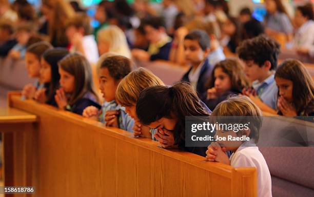 Children pray during a service, at St. Rose of Lima School, for the victims of the school shooting one week ago in Newtown, Connecticut on December...