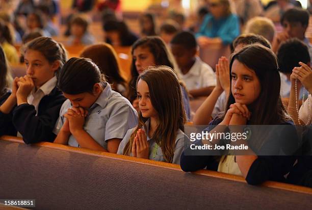 Grace Romanik, Jenny Rotondo and Victoria Gonzalez pray during a service, at St. Rose of Lima School, for the victims of the school shooting one week...