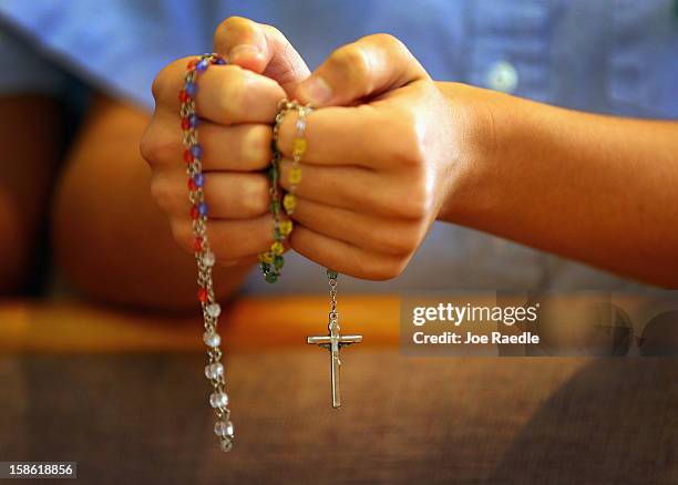 Child holds rosary beads as she prays during a service at St. Rose of Lima School, for the victims of the school shooting one week ago in Newtown,...