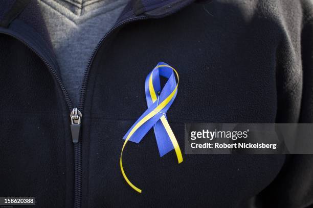 Local resident wears a ribbon December 15, 2015 honoring the 28 children and faculty shot and killed in Sandy Hook, Connecticut one day earlier on...