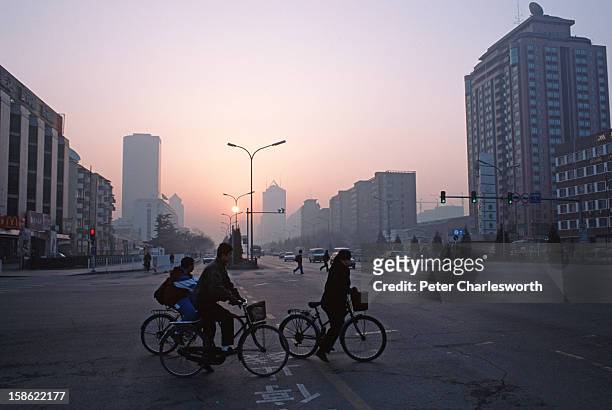 Cyclists head to work on Jianguomenwai Avenue at the crack of dawn..