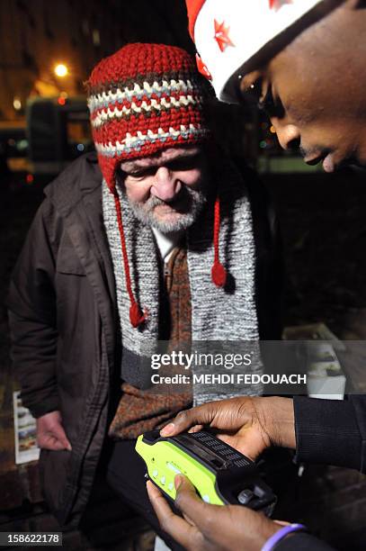 Member of the Association "Les Enfants du Canal" distributes a radio to a homeless man, in a street in Paris, on December 21, 2012. Thousands of...