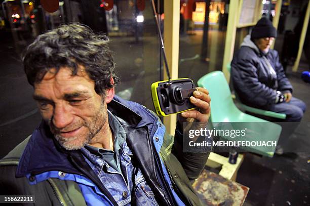 Homeless man listens to a radio distribued by members of the Association "Les Enfants du Canal", in a street in Paris, on December 21, 2012....