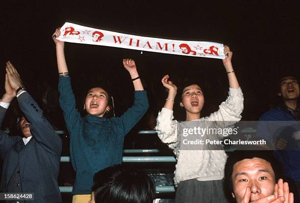 Fans dance in the aisle as they watch Wham including, George Michael and Andrew Ridgeley, playing a concert at Beijing's People's Stadium. This was...