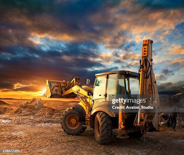 excavator en solar de construcción - máquina excavadora fotografías e imágenes de stock