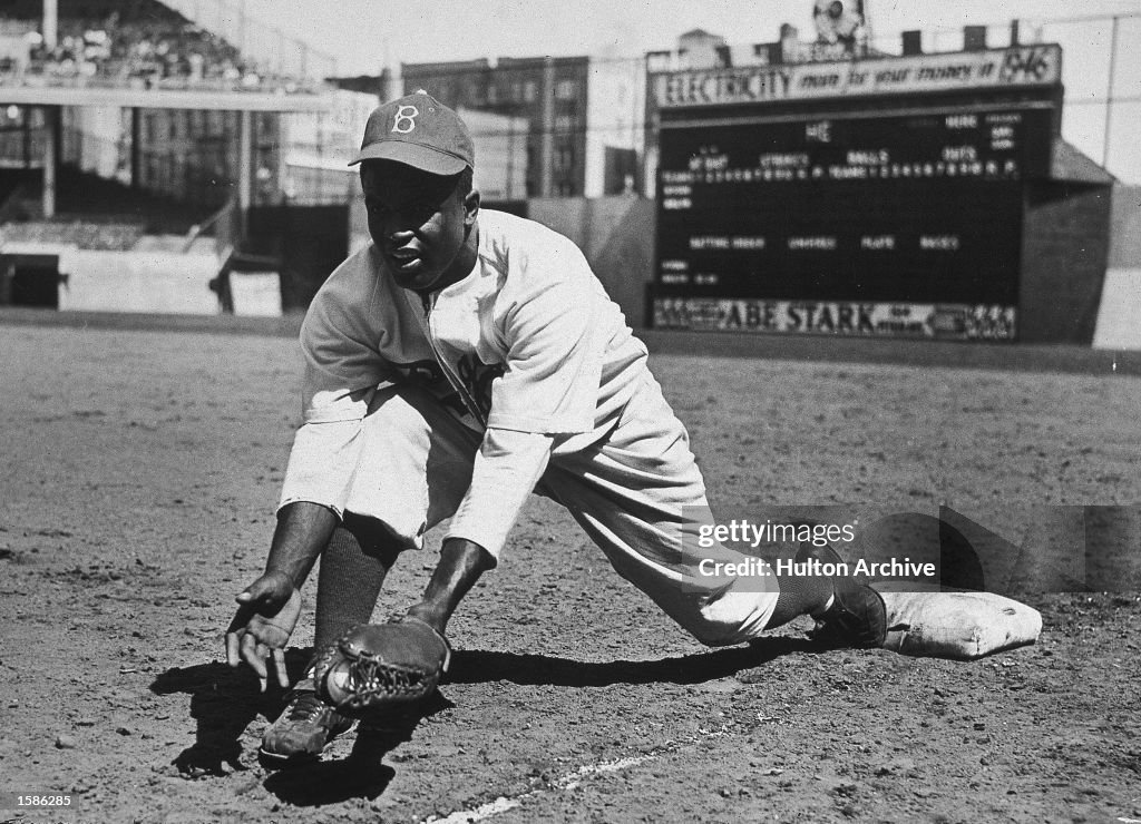 Jackie Robinson grounds ball at first base, 1950s.