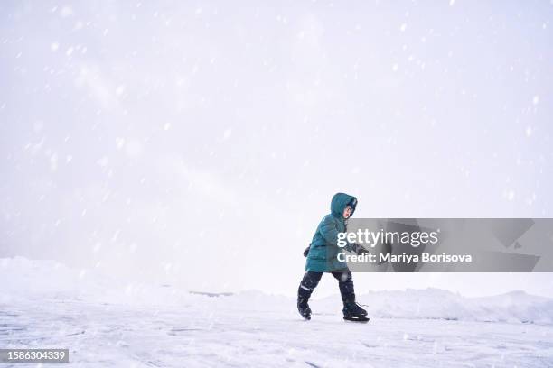 a child learns to skate on a makeshift ice rink on the lake. - figure skating child stock pictures, royalty-free photos & images