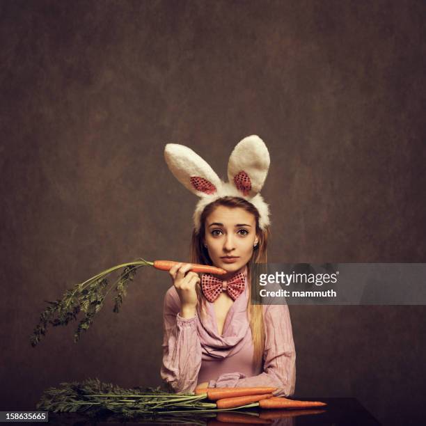 bunny girl holding a carrot - easter and humour stockfoto's en -beelden