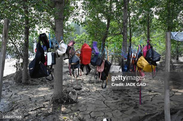 Handbags are hung to dry by a muddy street in the aftermath of flooding at a village after heavy rains in Zhuozhou city, in northern China's Hebei...