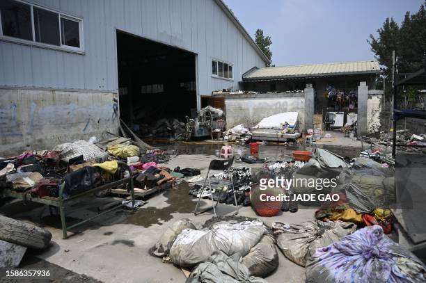 Bags and shoes are left to dry outside a warehouse in the aftermath of flooding at a village after heavy rains in Zhuozhou city, in northern China's...
