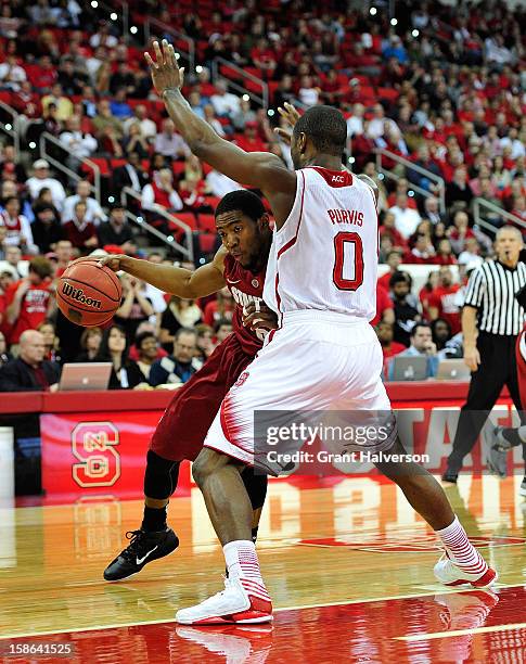 Chasson Randle of the Stanford Cardinal drives against Rodney Purvis of the North Carolina State Wolfpack during play at PNC Arena on December 18,...