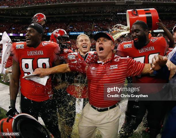 Head coach Mark Hudspeth of the Louisiana-Lafayette Ragin Cajuns is dunked with sports drink after defeating the East Carolina Pirates during the R+L...