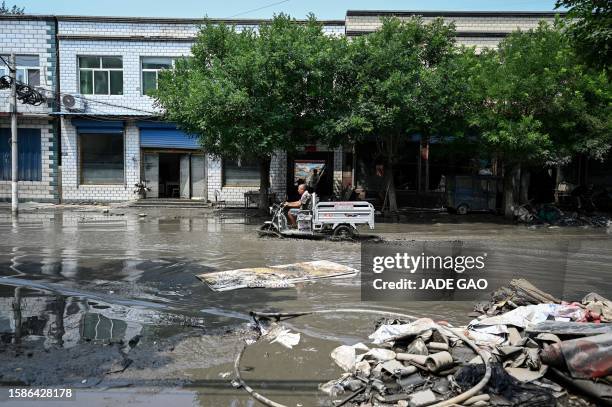 Local resident rides an electric tricycle along a flooded street in the aftermath of flooding from heavy rains in Zhuozhou city, in northern China's...