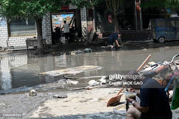 Flood-affected residents clean their houses in the aftermath of flooding from heavy rains in Zhuozhou city, in northern China's Hebei province on...