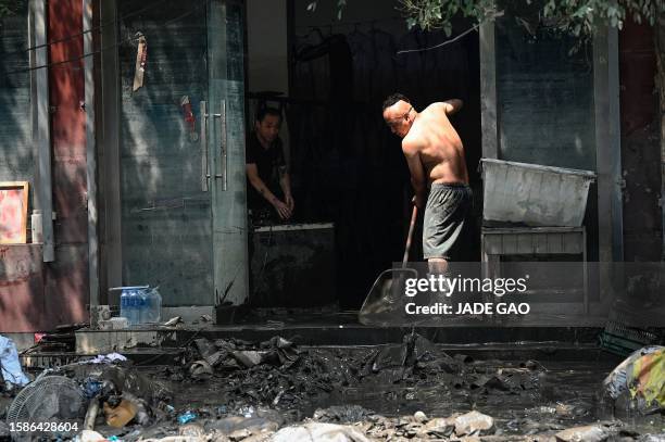 Flood-affected resident cleans his house in the aftermath of flooding from heavy rains in Zhuozhou city, in northern China's Hebei province on August...