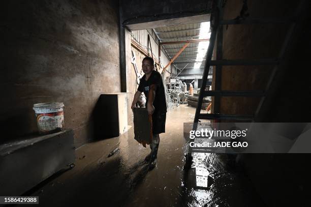 Worker clears debris from a warehouse in the aftermath of flooding from heavy rains in Zhuozhou city, in northern China's Hebei province on August 9,...
