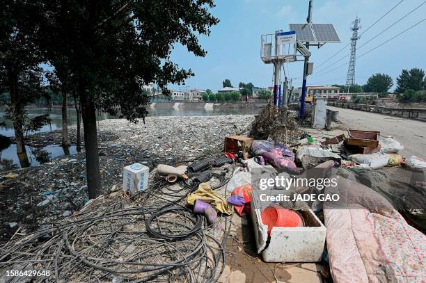 Debris is seen by a river bank and street in the aftermath of flooding from heavy rains in Zhuozhou city, in northern China's Hebei province on...