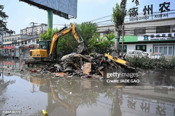 Worker clears debris from a street in the aftermath of flooding from heavy rains in Zhuozhou city, in northern China's Hebei province on August 9,...