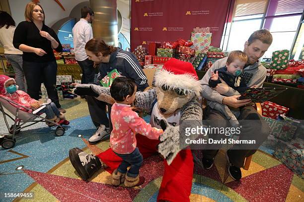 Mascot Crunch of the Minnesota Timberwolves hugs a young patient while Lou Amundson and Luke Ridnour distribute holiday gifts collected through the...