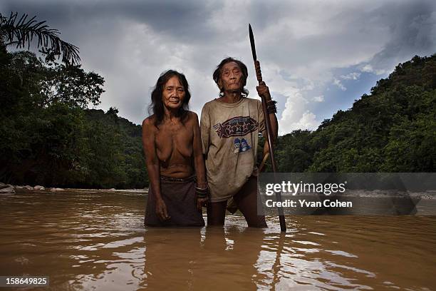 An elderly Penan couple stand for a symbolic portrait in the river near their longhouse in an area known as Long Napir. A new dam project threatens...