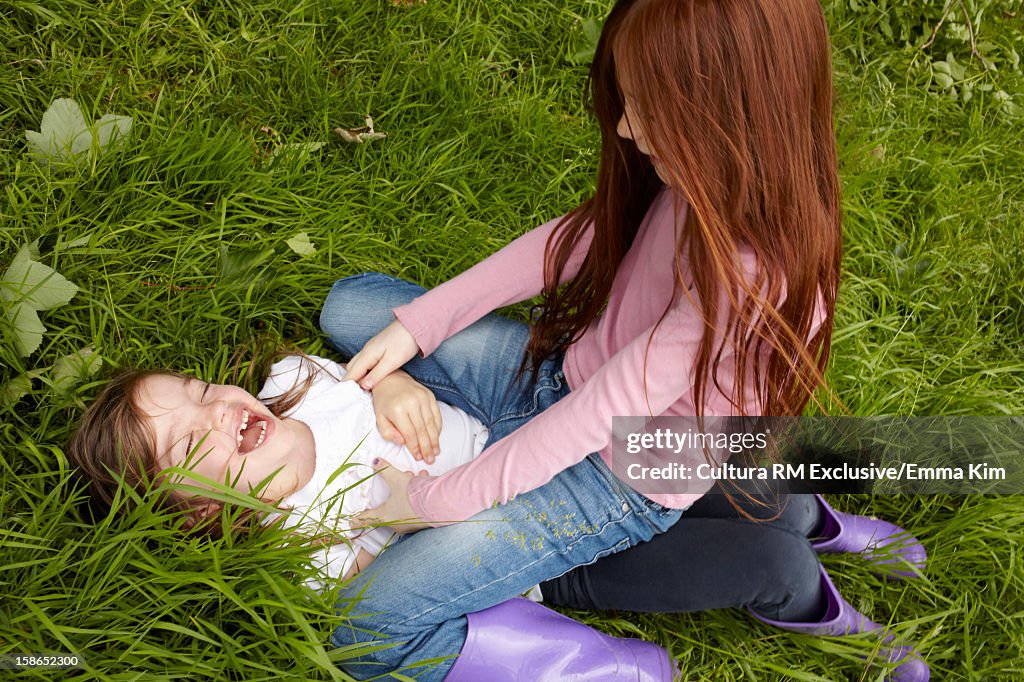 Laughing girls playing in grassy field