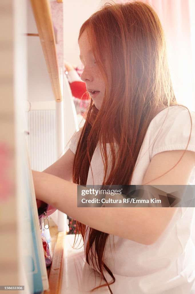 Girl rummaging in bathroom cabinet