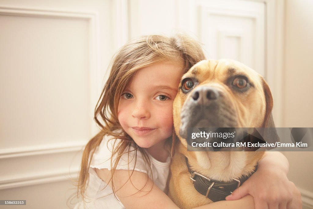 Girl hugging dog indoors