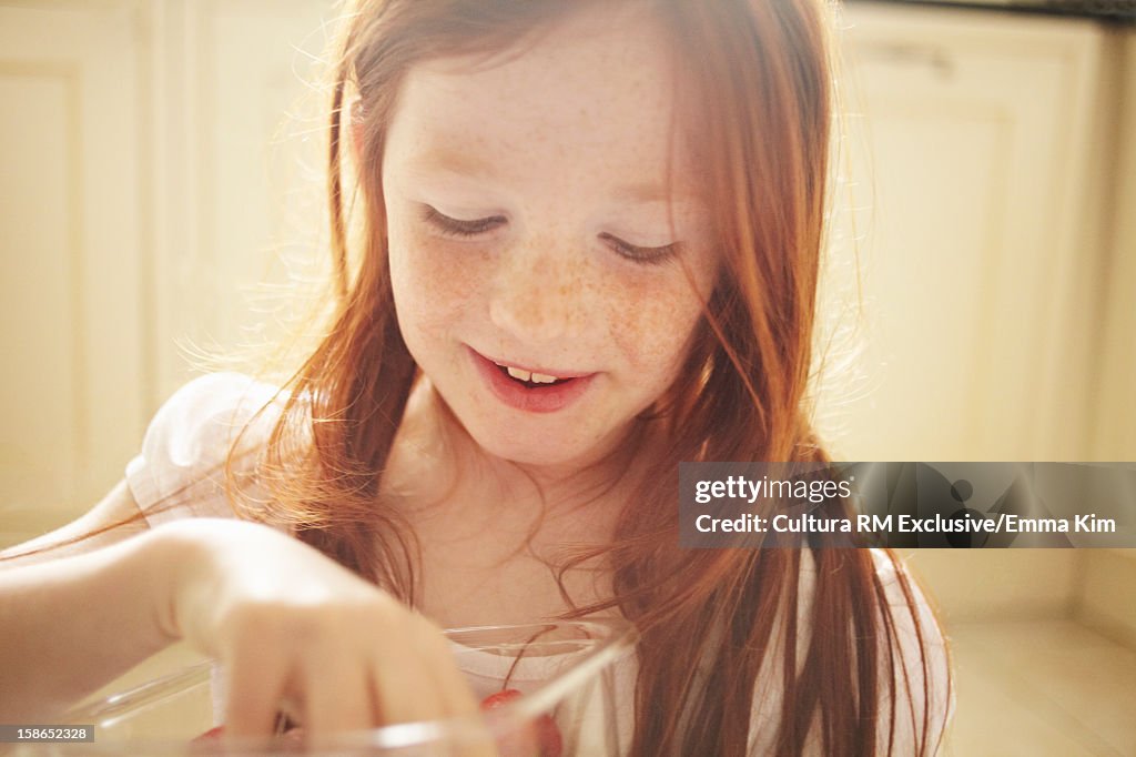 Girl eating strawberries in kitchen