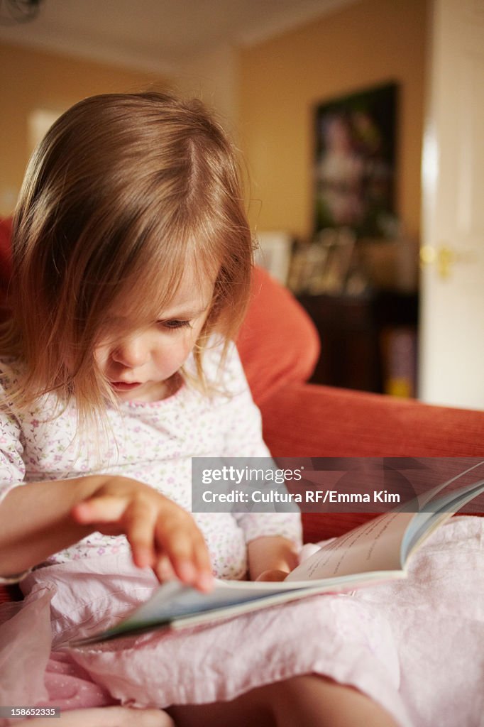 Girl reading book in armchair