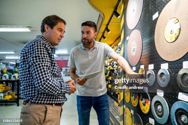 verkäufer hilft einem kunden beim einkaufen in einem baumarkt - elektrisches werkzeug stock-fotos und bilder