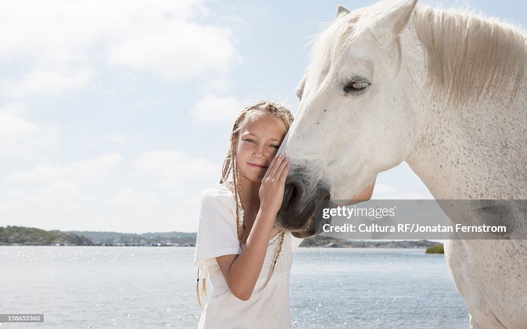 Girl petting horse on sandy beach