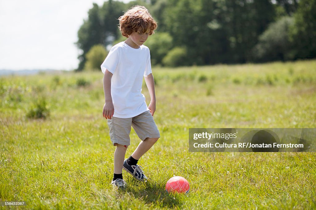 Girl kicking soccer ball in grassy field
