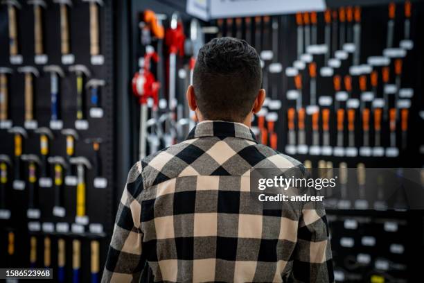 rear view of a man shopping for tools at a hardware store - zzp'er bouw stockfoto's en -beelden