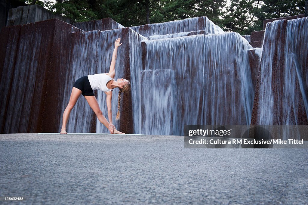 Woman practicing yoga at public fountain