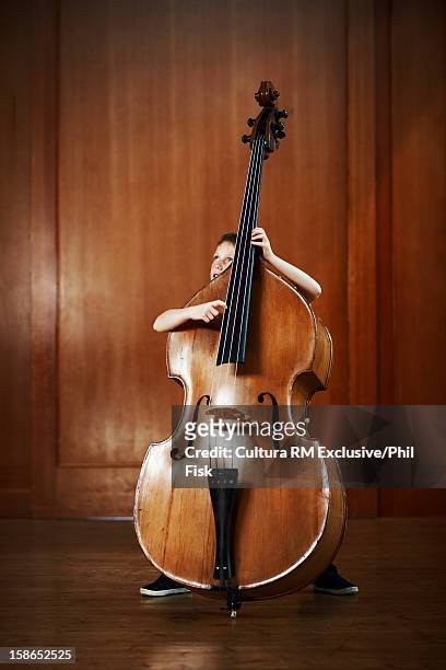 boy playing oversized cello - kontrabass stock-fotos und bilder