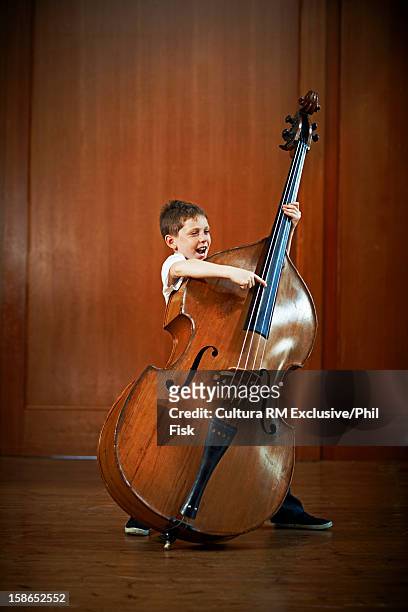 boy strumming oversized cello - double bass stock pictures, royalty-free photos & images