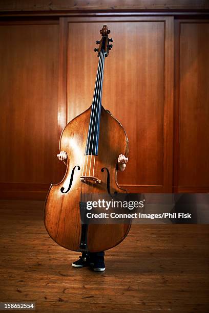 boy holding oversized cello - instrumento-baixo imagens e fotografias de stock