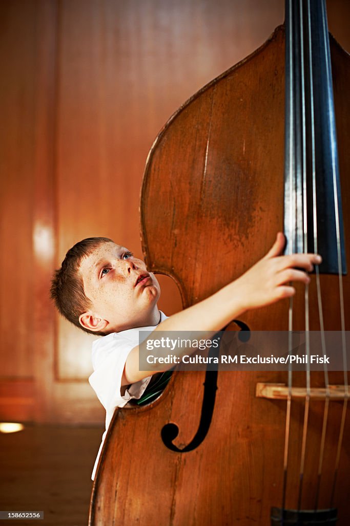 Boy strumming oversized cello