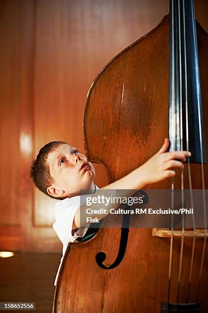 boy strumming oversized cello - double bass stock pictures, royalty-free photos & images