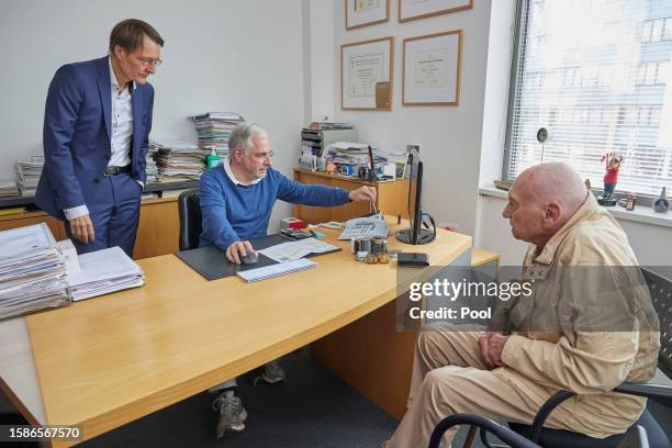 German Health Minister Karl Lauterbach observes as doctor Benny Levenson inserts the health insurance card of 86-year-old Peter Jordan into a...
